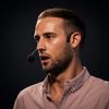 Side-profile portrait of a person wearing a headset microphone and a light button-down shirt, speaking against a dark background.
